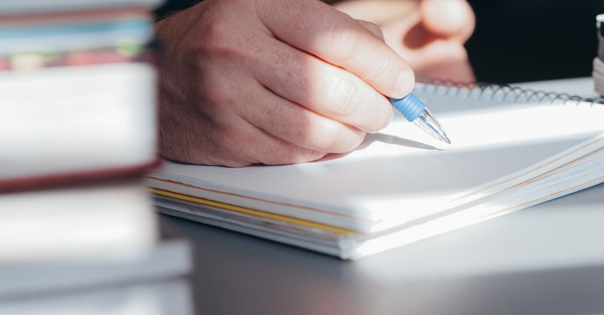 Profissional analisa um currículo aberto no notebook e uma versão impressa sobre a mesa